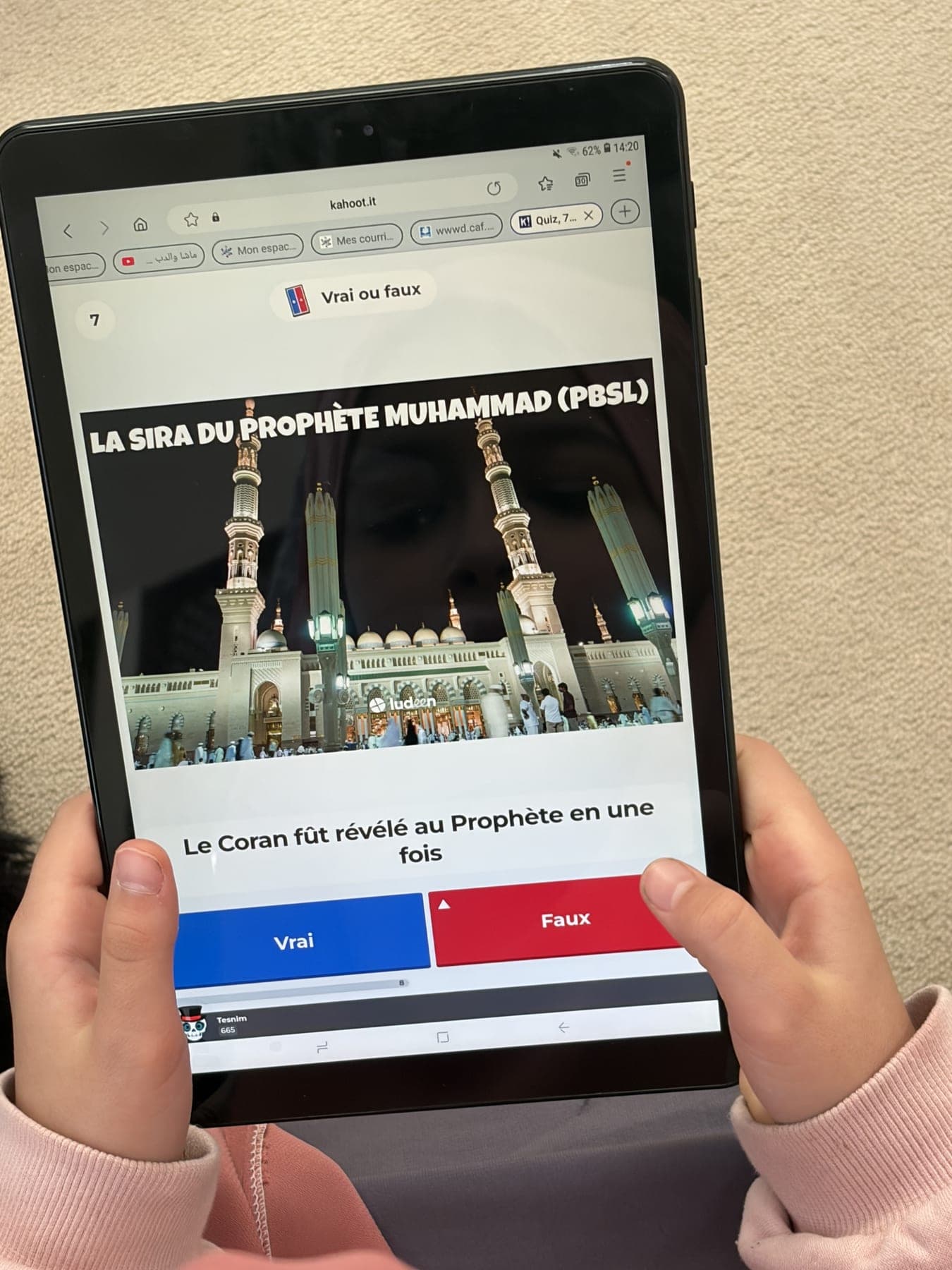 Une participante tenant une tablette qui affiche une question du quiz sur la Sira du Prophète
